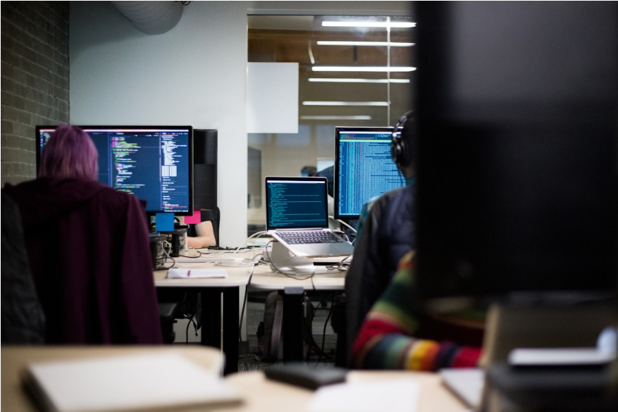 People collaborating at computers in an office, focusing on integrating Fax API into software for unified communications.
